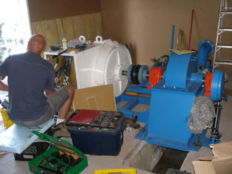 Wiring the 75 kW generator coupled to 60 kW turbine. Hydraulic controls on spear valve and deflector for fully automatic control. Turbine sump still visible, later covered with access hatch.